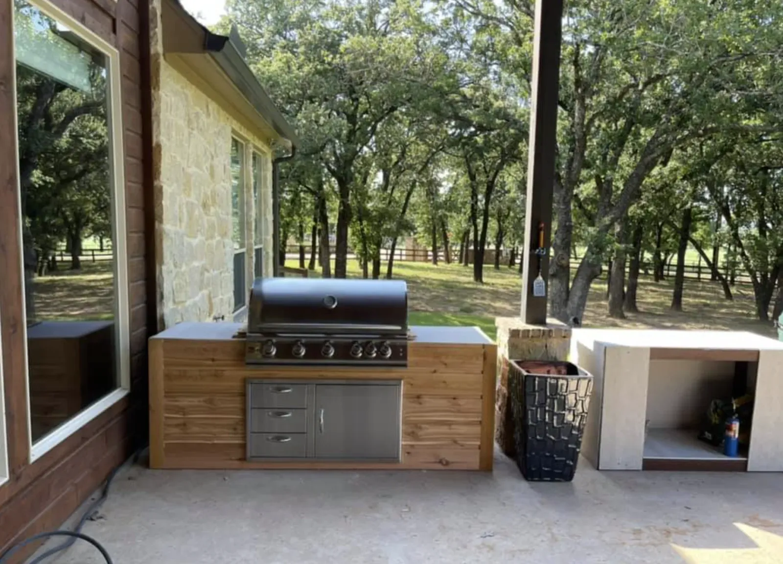 Covered outdoor kitchen with grill, stone counter, and dining space